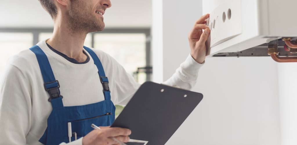 Professional plumber checking a boiler control panel, he is adjusting a knob Professional plumber checking a boiler control panel, he is adjusting a knob